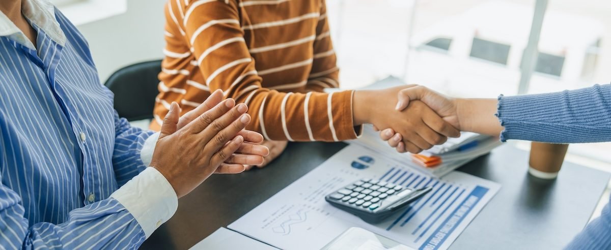 Shaking hands, Close up group of business woman discussion and brainstorming, bookkeeping audit graph and chart documents at desk, teamwork concept.